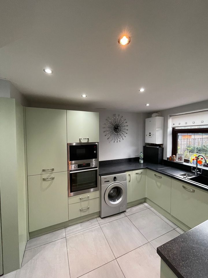 Pale sage slab kitchen with integrated ovens