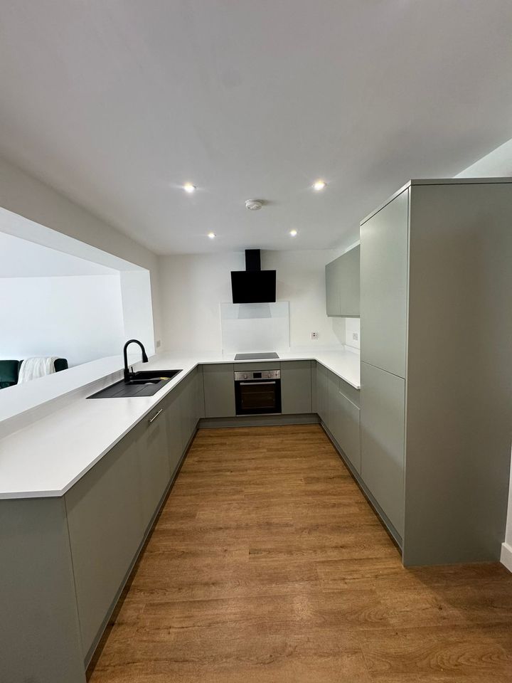 Sage-grey handleless kitchen with white quartz worktops after respraying