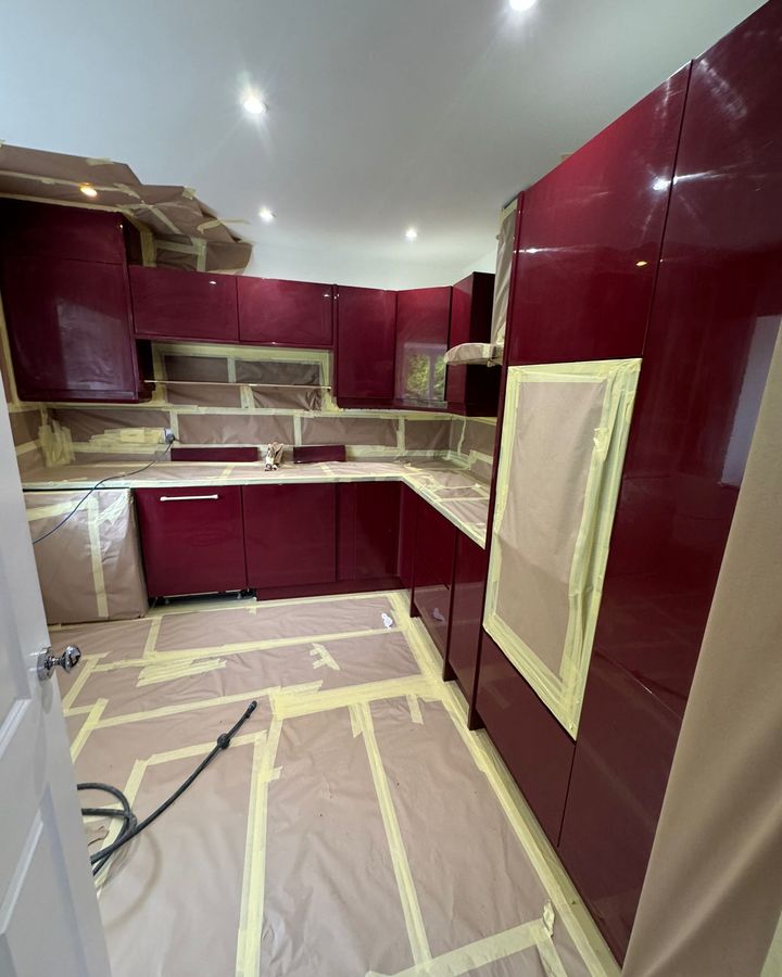 A burgundy kitchen fully masked with paper, tape and floor protection before spraying