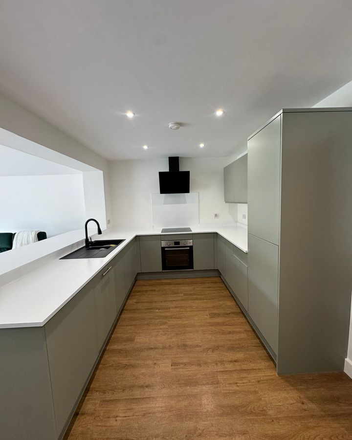 A finished sage-grey handleless kitchen after the masking comes down